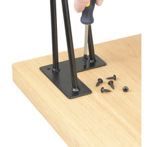 Montáž čiernych stolových nôh pomocou skrutiek na stolovú dosku.