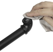 Ruka čistí čiernu rúrkovú armatúru handričkou.