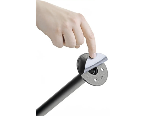 Ruka odstraňuje ochrannú fóliu z rúrkovej príruby na montáž na stenu.