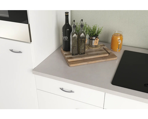 Kuchynské zátišie s doskami na krájanie, fľašami na olej, bylinkami a nápojom na pracovnej doske