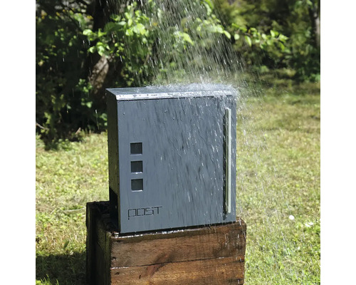 Dážď padá na sivú poštovú schránku na drevenej debne.