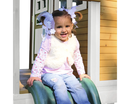 Dievča sa šmýka na zelenej šmýkačke pred domčekom na hranie