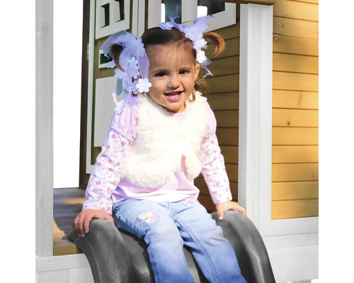 Dievča sa kĺže na detskej šmýkačke v detskom domčeku