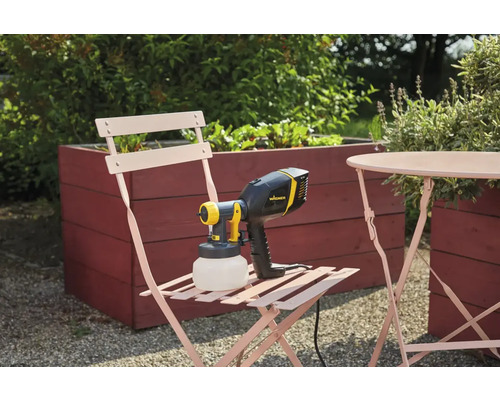 Striekací systém Wagner na záhradnej stoličke vedľa stola a vyvýšeného záhona