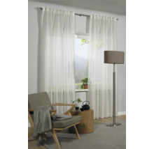 Obývacia izba s bielymi priehľadnými závesmi, kreslom, príručným stolíkom a stojacou lampou.