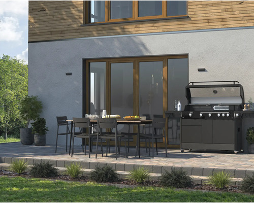 Terasa s jedálenským stolom, stoličkami a plynovým grilom pred rodinným domom.