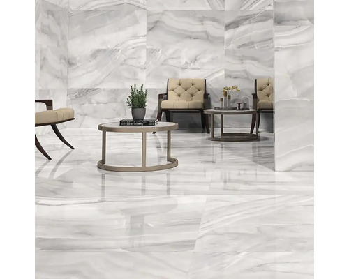 Svetlá miestnosť s podlahovými a nástennými dlaždicami so vzhľadom mramoru, vybavená kreslami a stolmi.