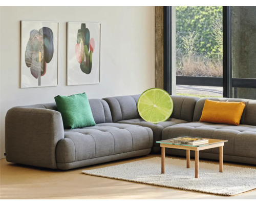 Sivá rohová sedačka s vankúšmi, konferenčný stolík a zarámované umelecké diela v obývacej izbe