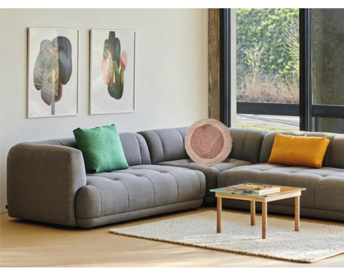 Obývacia izba so sivou rohovou sedačkou, ozdobné vankúše, konferenčný stolík a umenie na stene