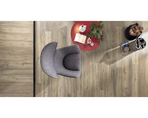 Pohľad zhora na miestnosť s laminátovou podlahou so vzhľadom dreva, kreslom, stolom a dekoráciami.