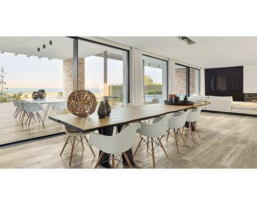 Svetlá obývacia izba s jedálenským stolom, stoličkami, veľkými oknami a výhľadom na more