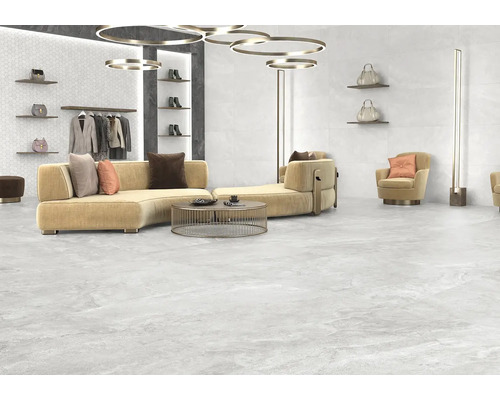 Svetlá, priestranná obývacia izba s pohovkou, kreslom a svetlou kameninovou dlažbou.