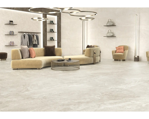 Svetlá izba s pohovkou, kreslom, policami a podlahovými dlaždicami.