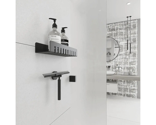 Moderná kúpeľňa s poličkou, stierkou na sprchy a dekoratívnou stenou.