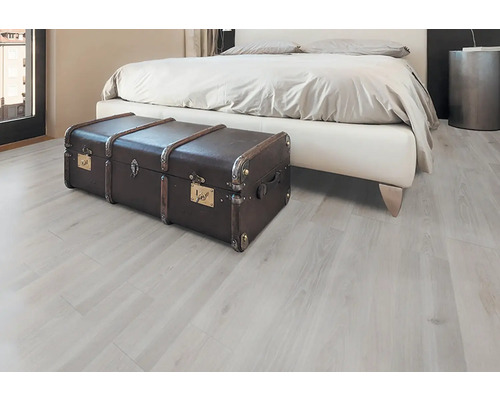 Spálňa so svetlou drevenou podlahou a hnedou truhlou