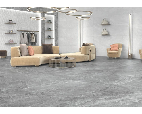 Svetlá izba s pohovkou, kreslami, osvetlením a sivou dlažbou.