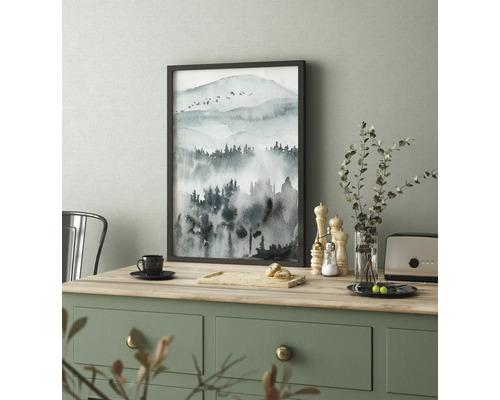 Zarámovaný obraz s akvarelom horskej krajiny na stole