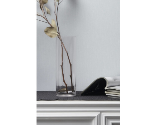 Ozdobné konáre v sklenenej váze vedľa časopisov na komode