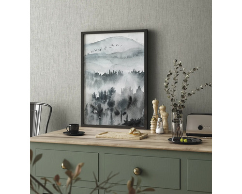 Dekoratívny obraz s motívom hory v ráme na kuchynskom stole.