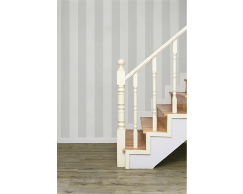 Schodisko s drevenými schodmi a bielym zábradlím pred pruhovanou stenou