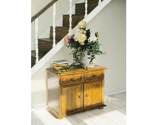 Scéna s drevenou komodou, knihami a kvetmi pod schodmi