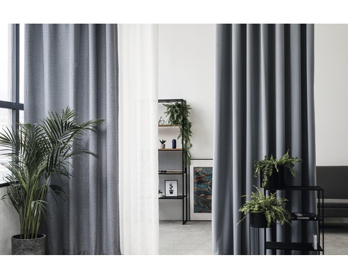 Obývacia izba so závesmi, regálom a izbovými rastlinami.