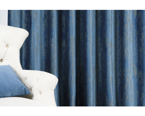 Dekoratívny modrý záves s vertikálnym vzorom vedľa kresla.