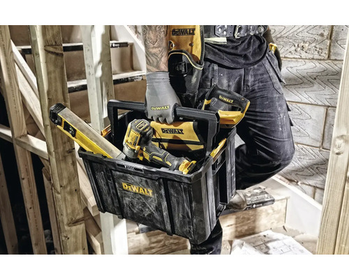 Remeselník s boxom na náradie, vodováhou, skrutkovačom a opaskom na náradie DeWalt na drevenom schodisku.
