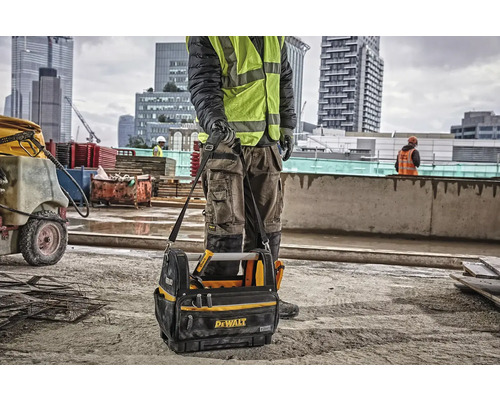 Stavebný robotník s brašnou na náradie značky Dewalt na stavenisku.