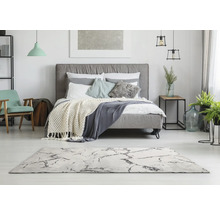 Svetlá spálňa s posteľou, kobercom a dekoráciami pre príjemnú atmosféru.