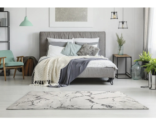 Svetlá spálňa s posteľou, kobercom a dekoráciami pre príjemnú atmosféru.