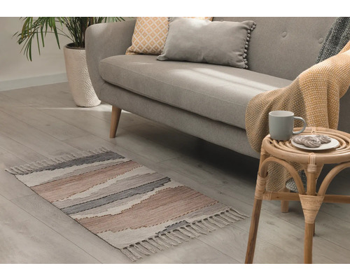 Obývacia izba s pohovkou, izbovou rastlinou a vzorovaným kobercom