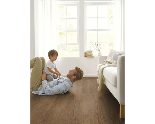 Otec a dieťa sa hrajú na drevenej podlahe v svetlej obývacej izbe.