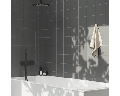 Kúpeľňa so sivými dlaždicami, vaňou, uterákom a sprchou