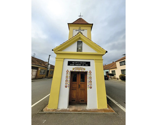 Malá kaplnka s drevenými dverami a krížom na streche