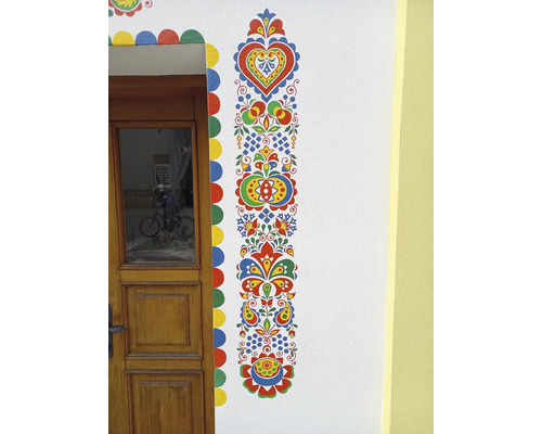 Maľovaná fasáda domu s kvetinovými motívmi a drevenými dverami