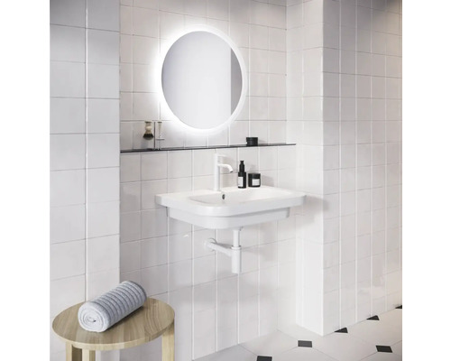 Kúpeľňa s bielym umývadlom, okrúhlym zrkadlom s osvetlením a uterákom na stoličke