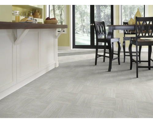 Svetlá miestnosť s dlažbou v štvorcovom usporiadaní a kuchynským ostrovčekom s barovými stoličkami