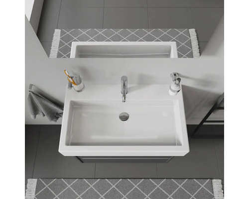 Snímka bieleho umývadla s vodovodnou batériou, dávkovačom mydla a držiakom na uteráky v kúpeľni