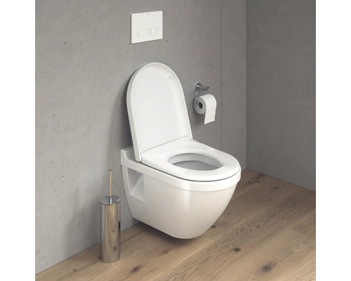 Závesné WC s otvoreným splachovacím kruhom, ovládaním splachovania, držiakom toaletného papiera a WC kefou v kúpeľni.