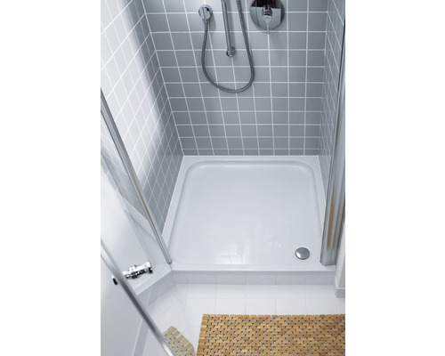 Sprchovací kút so sprchovacou vaničkou, armatúrou a sivo obloženou stenou