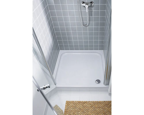 Sprchovací kút v úrovni podlahy so sprchovacou vaničkou, sprchovacou armatúrou a sprchovacou zástenou so sivými obkladmi