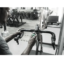 Mechanik nastavuje riadidlá pretekárskeho bicykla nástrojom v dielni.