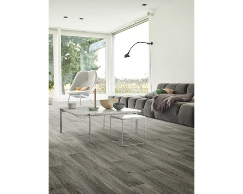 Svetlá obývacia izba so sivou drevenou podlahou, pohovkou, stolom a stoličkou