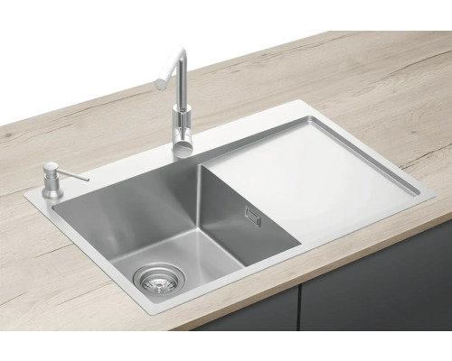 Nerezový drez s odkvapkávacou plochou, vodovodnou batériou a dávkovačom mydla na pracovnej doske.