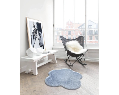 Obývacia izba s kobercom v tvare oblaku, lavicou, kreslom a zarámovaným plagátom