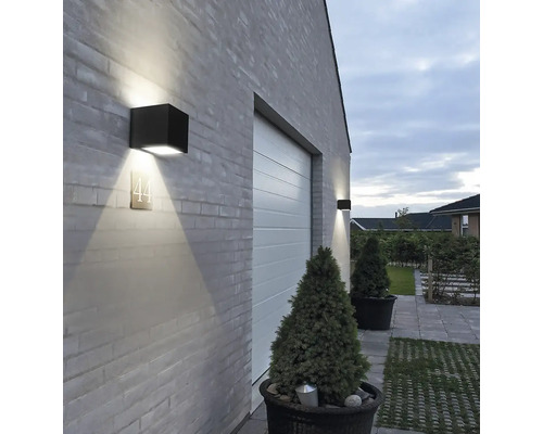 Fasáda domu s dvoma kubickými vonkajšími svetlami a číslom domu vedľa garážovej brány