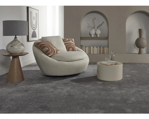 Interiérová fotografia obývacej izby so sivým kobercom, kreslom, stolom a dekoratívnymi prvkami