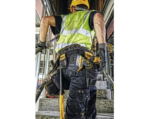 Stavebný robotník s opaskom na náradie a bezpečnostnou vestou na stavenisku