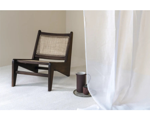 Scéna s tmavou drevenou stoličkou s ratanovým sedadlom, džbánom a šálkou na podnose a priehľadným závesom.